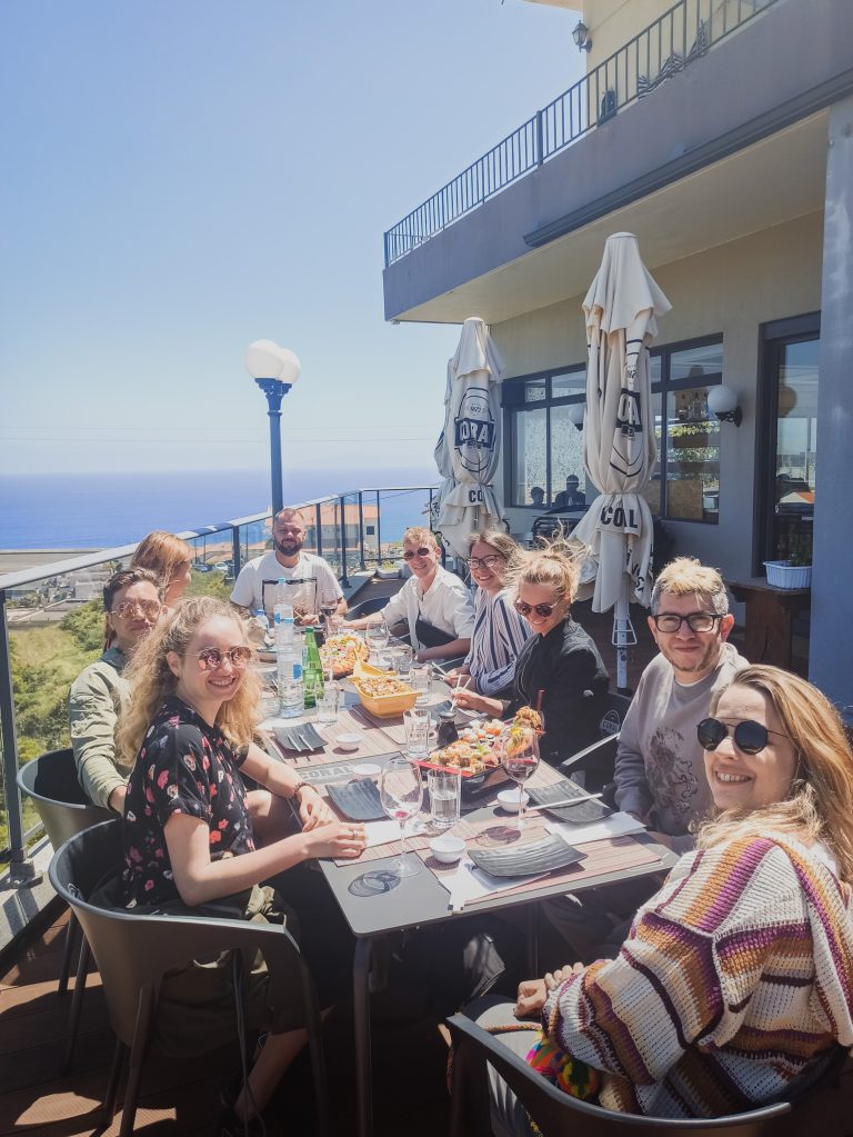Community lunch at a long table by the sea